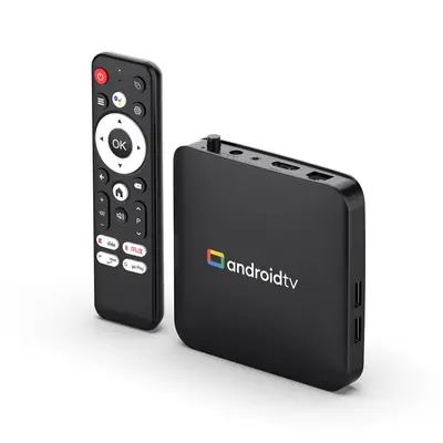 A black Android TV box next to its remote control with streaming shortcut buttons