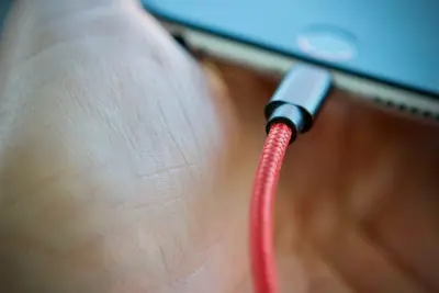 A charging cable plugged into a smartphone held in a hand
