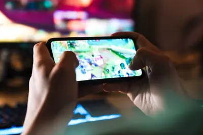 Close-up of hands holding a smartphone in landscape mode playing a mobile game